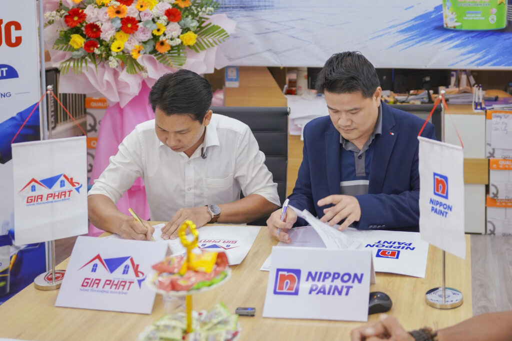 Two executives seated at a table signing the official distribution agreement document for the Mekong Delta.