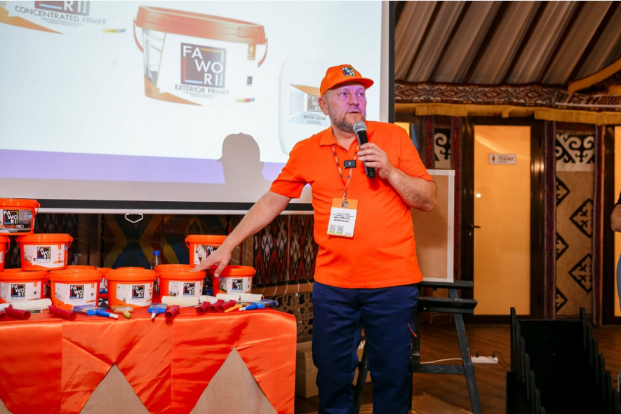 A presenter wearing orange Fawori branded clothing introducing durable paint coatings at a launch event.