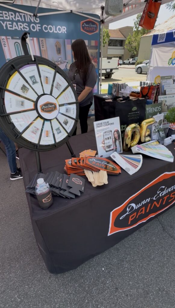 An interactive Dunn-Edwards booth featuring a prize wheel, paint samples, and promotional merchandise.