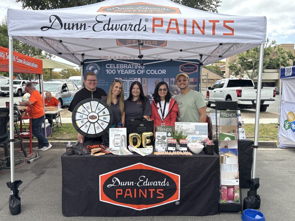 A team of five employees posing behind a Dunn-Edwards Paints booth at an outdoor fair.