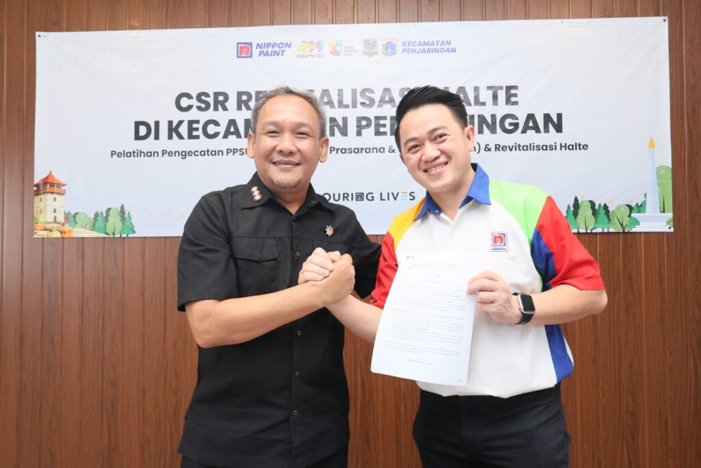 Two men smiling and shaking hands while displaying a formal partnership document.