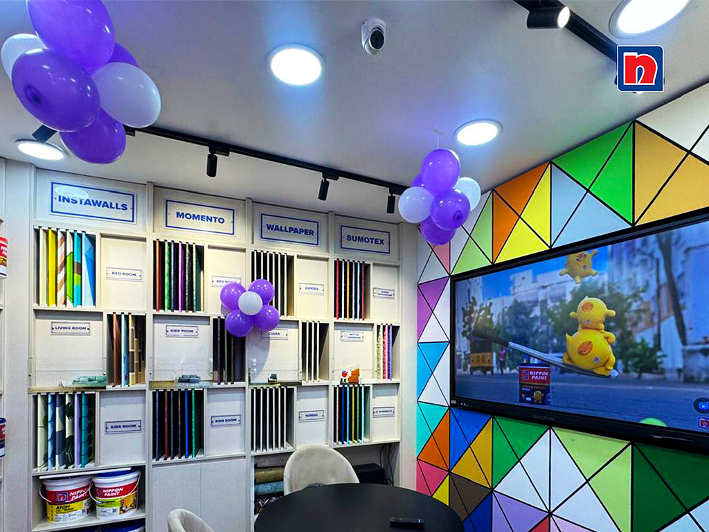 Modern interior showroom displaying paint finishes, wallpaper samples, and an interactive digital display screen.
